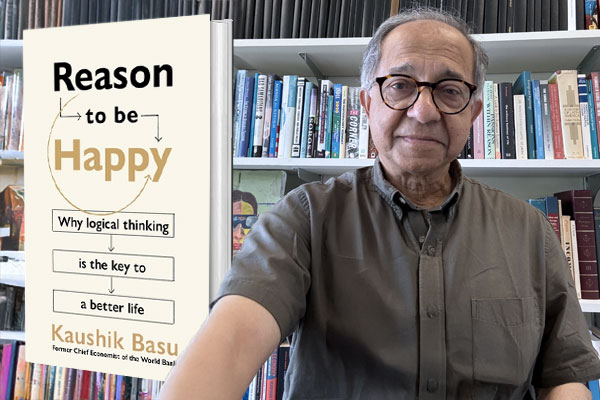 Man stands in front of a book shelf and to his left is an enlarged image of the book he authored.