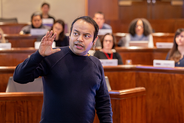 A professor teaching a class at the front of a classroom.