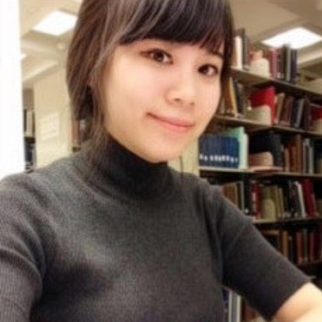 Young woman in a sweater in college library looking at camera and smiling