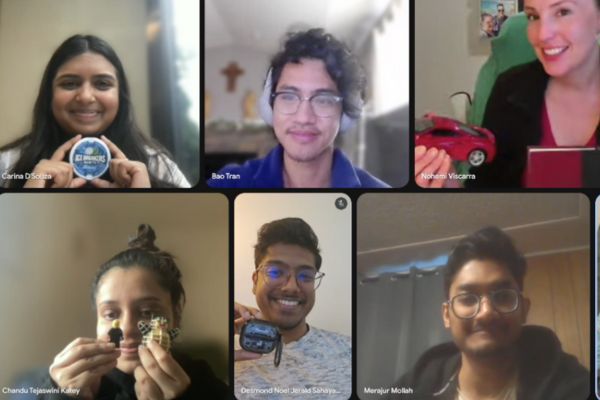 A group of six people smiling during a virtual meeting; each person is holding up an object