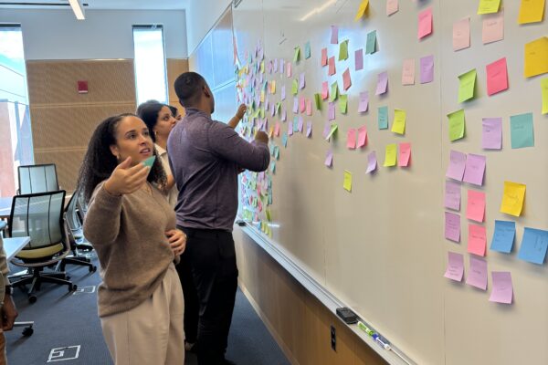 MBA students organize post-its on a white board during a classroom activity